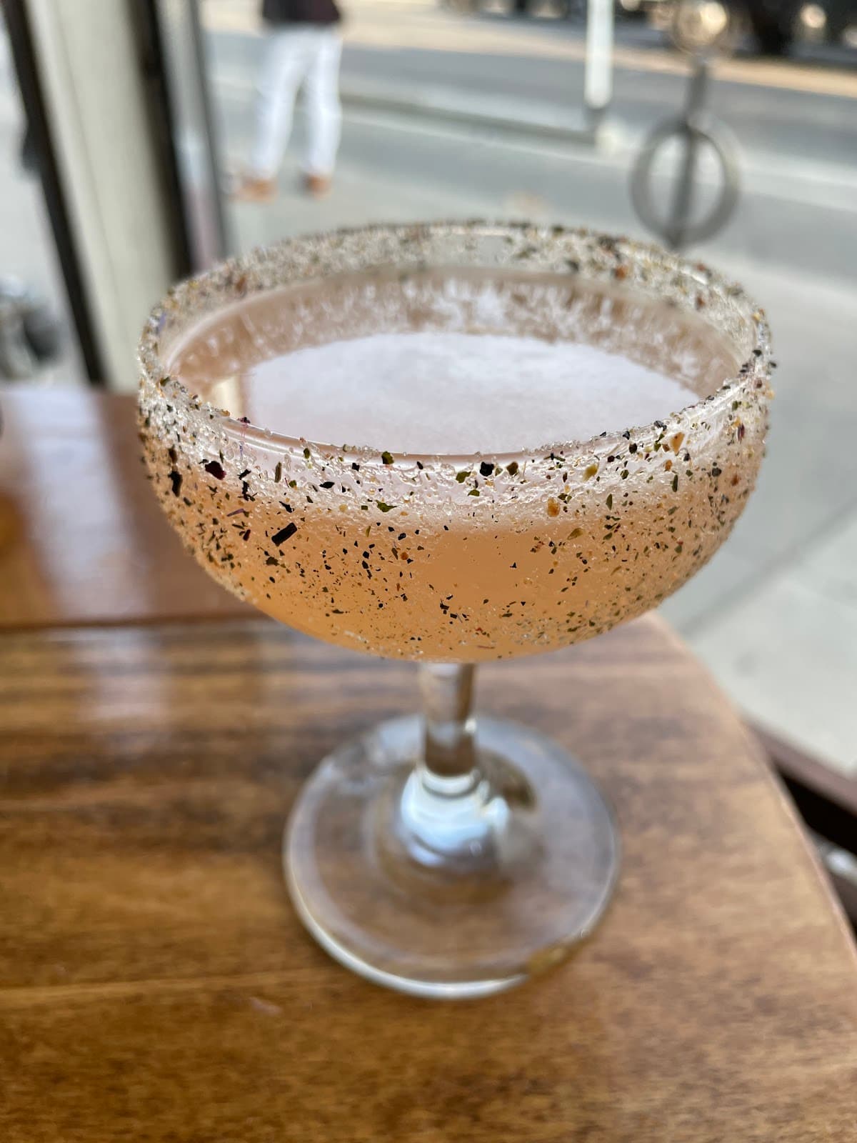 Close-up of a cocktail with a seasoned rim on a wooden table near a window in Toronto