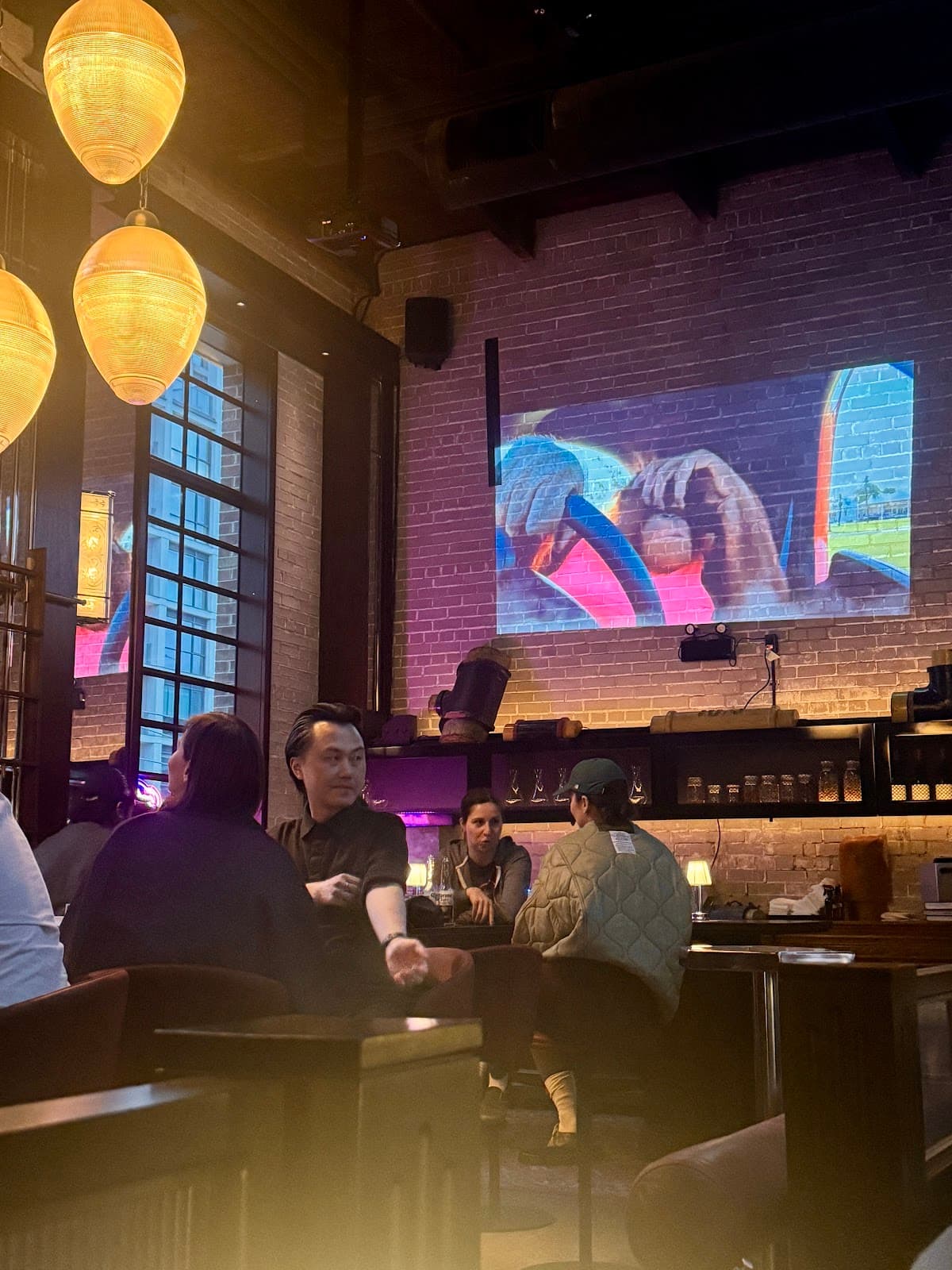 Cozy interior with patrons seated and brick walls with video projection in Toronto