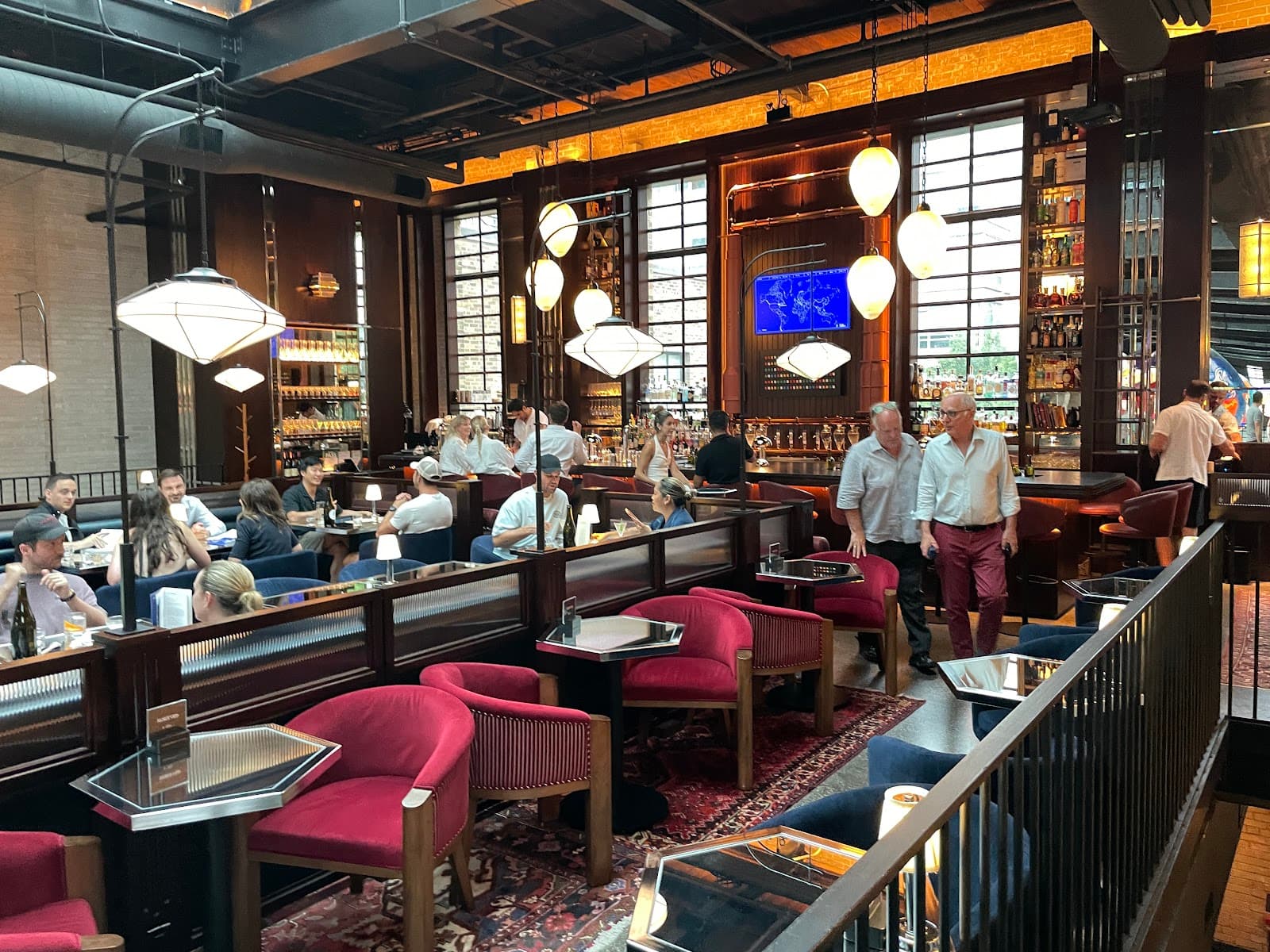 Interior of a stylish cocktail bar with red chairs and patrons