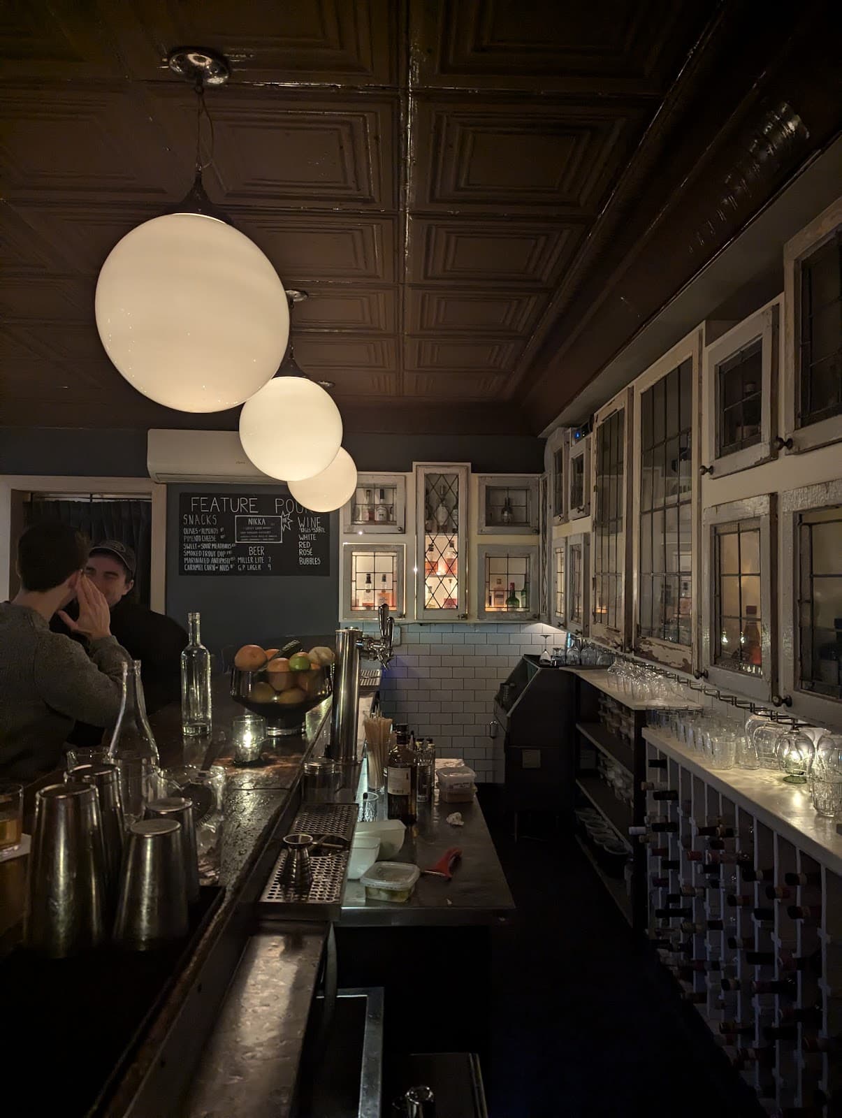 Cozy bar interior with hanging lights and a wide array of drinks.