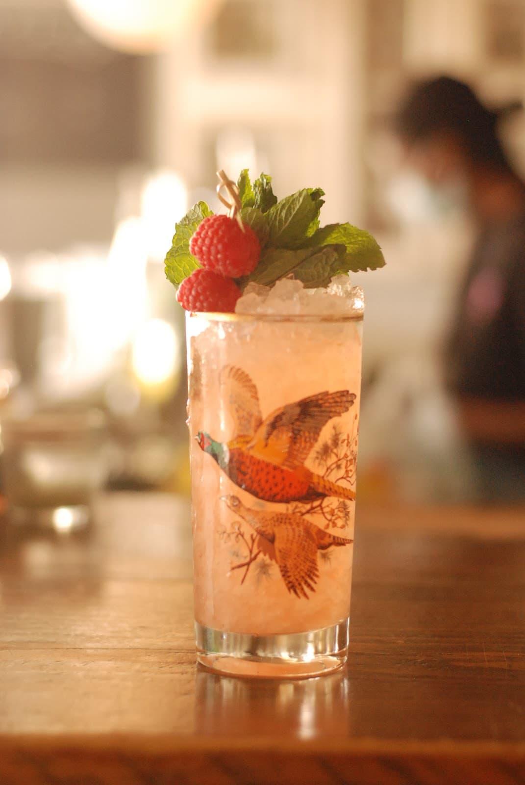 Refreshing cocktail with mint and raspberry garnish on wooden bar in Toronto