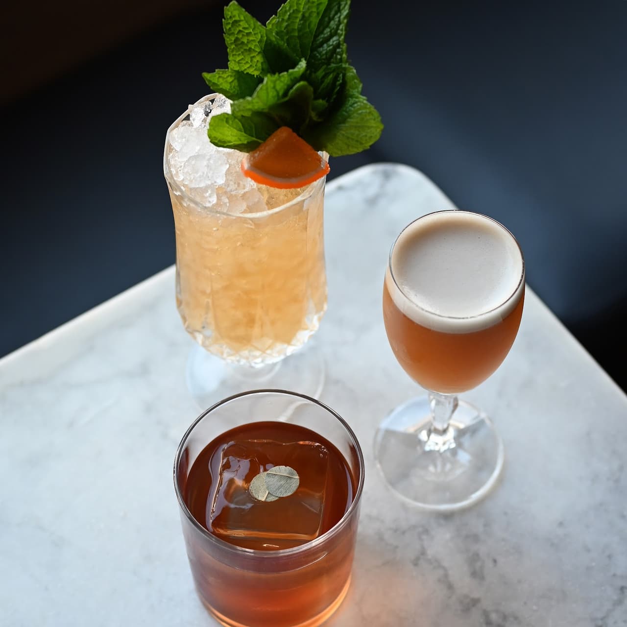 Three elegant cocktails on a marble table at a bar in Toronto