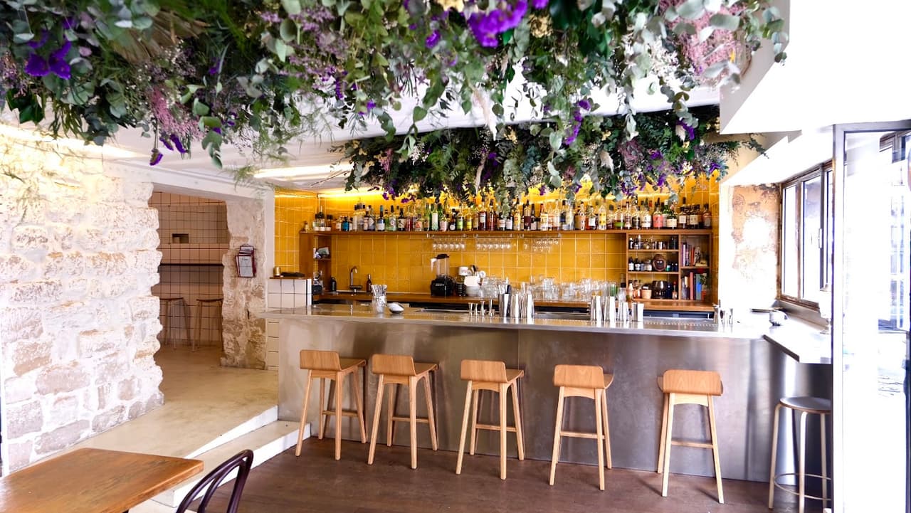 Stylish bar with yellow tiles, wooden stools, and hanging greenery decor