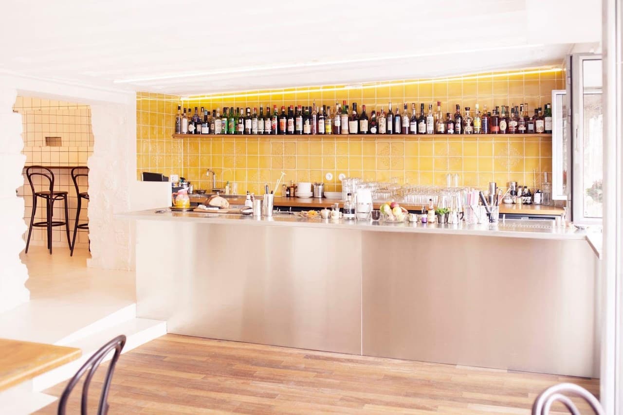 Bright bar area with yellow tiles and bottles lined up in Paris