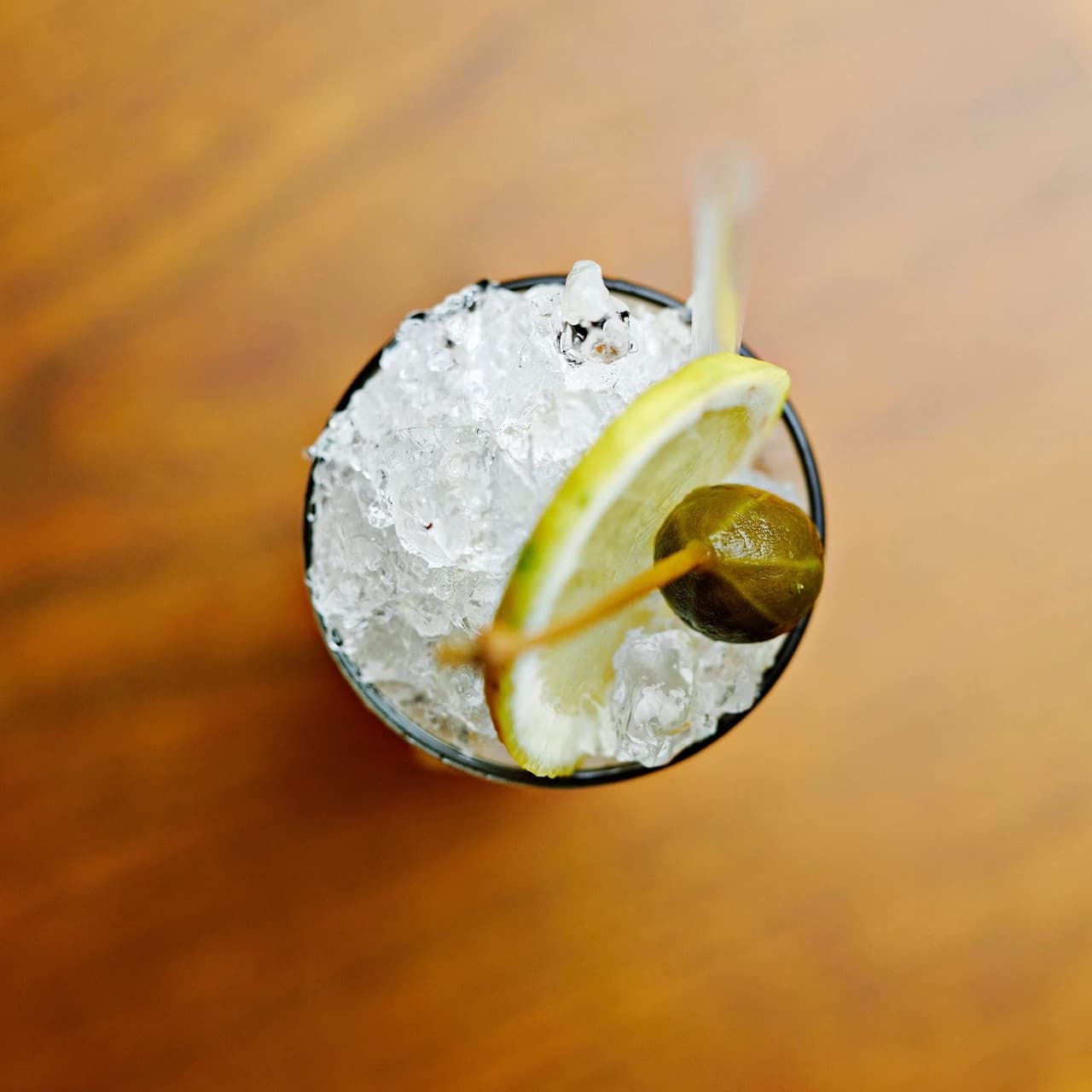 Top view of cocktail with ice and lemon garnish on wooden surface in Paris