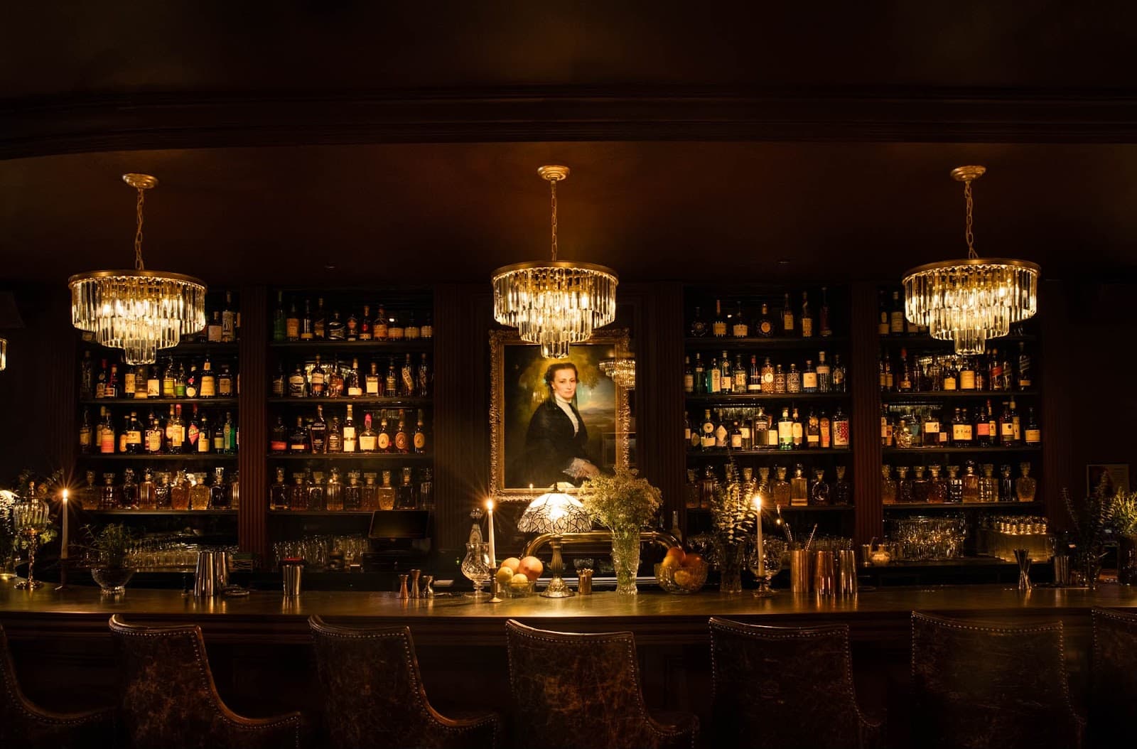 Elegant bar with chandeliers and bottles on shelves in a dimly lit setting
