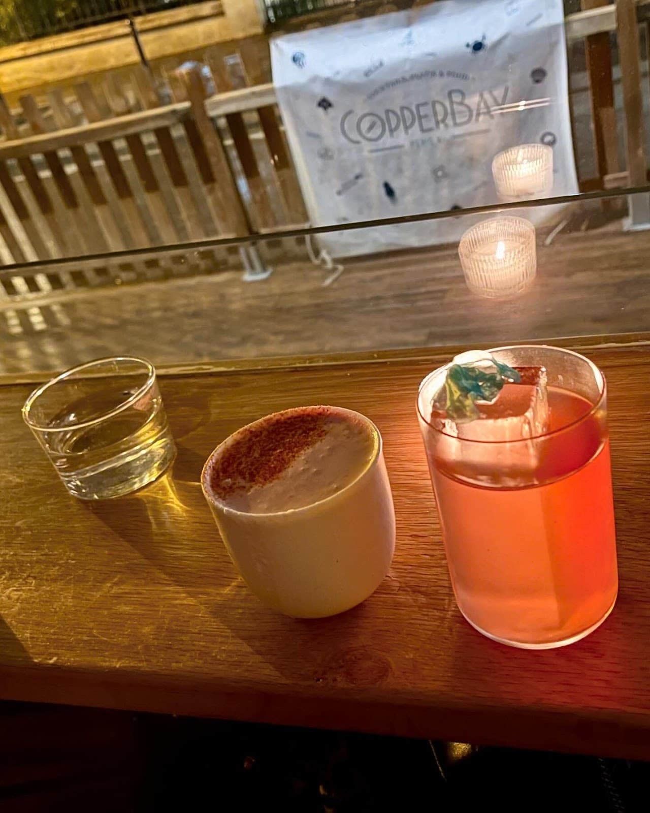 Cocktails on a wooden bar with a dimly lit background at CopperBay in Paris
