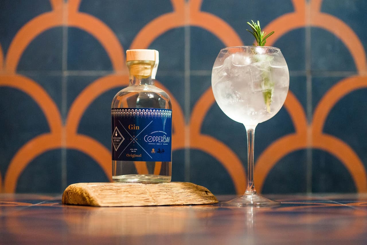 Gin bottle and cocktail glass on patterned surface, Copper Bay Paris in Paris