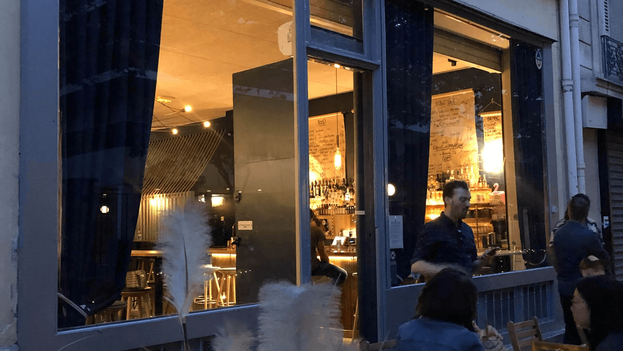 Exterior view of cocktail bar with large windows and patrons outside