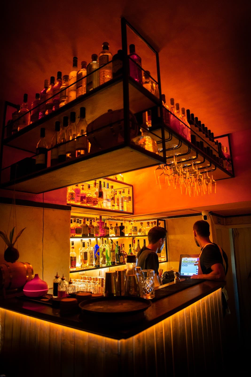 Warmly lit bar area with bottles and a bartender. in Lisboa