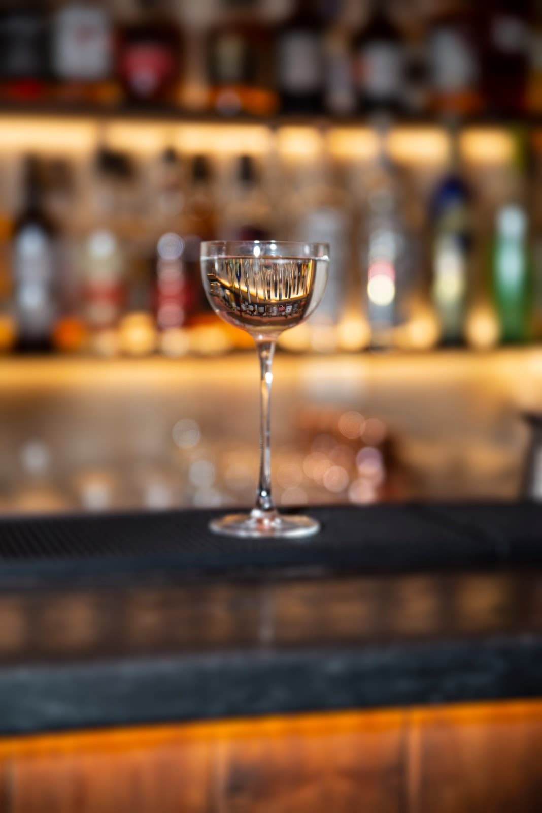 Close-up of cocktail glass on a bar with blurred bottles in background in Lisboa