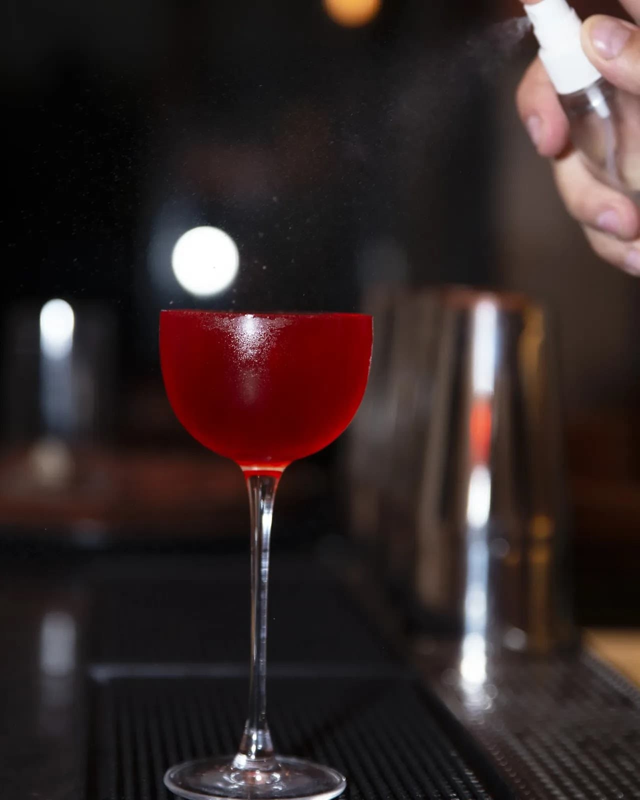 Red cocktail with garnish spray on a bar counter in Lisboa