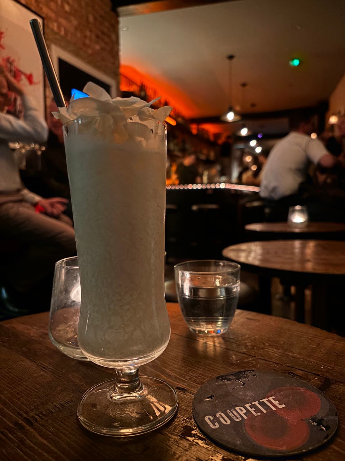 Cocktail with whipped cream in a bar, Coupette coaster visible in London