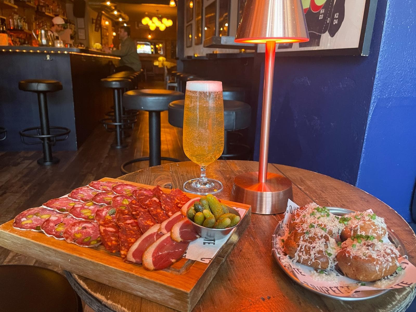 Cozy bar interior with charcuterie platter and beer on a table in London