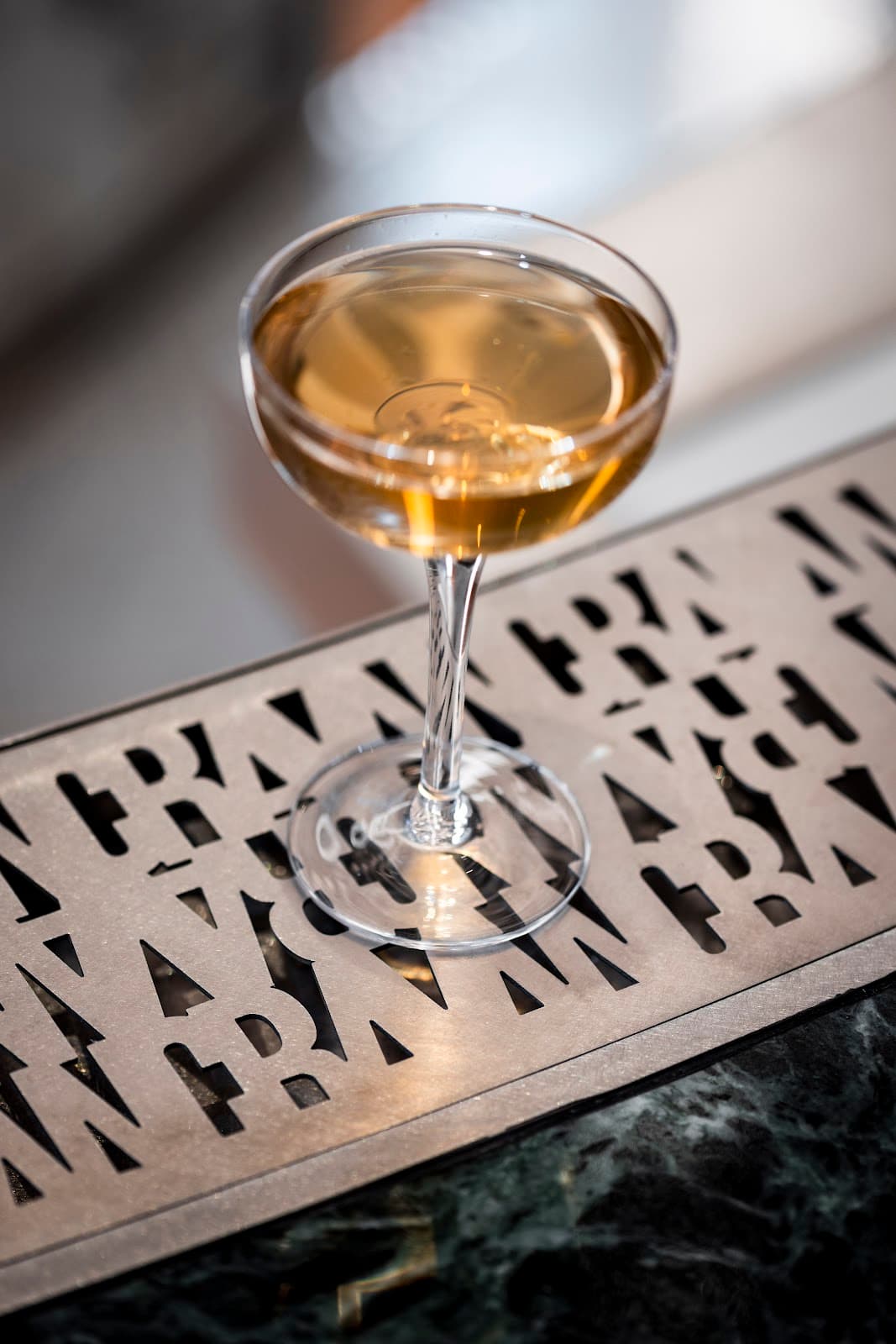Close-up of a cocktail glass on a stylized metal bar counter in Paris