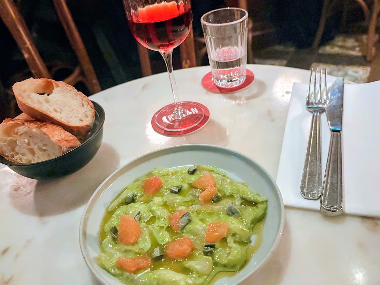 Table with a glass of red drink, bowl of bread, and a plate of food in Paris
