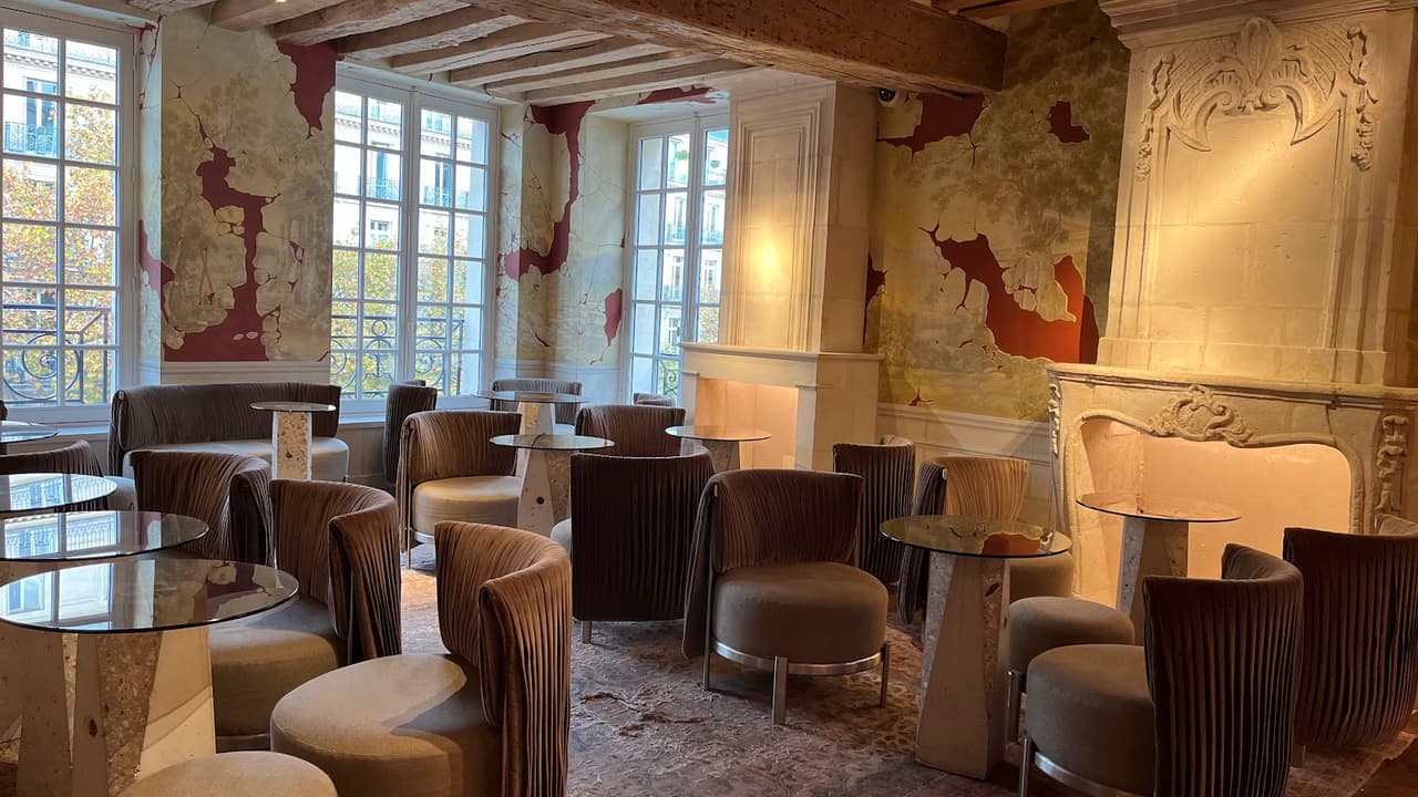 Chic interior with round tables and plush chairs near large windows in Paris