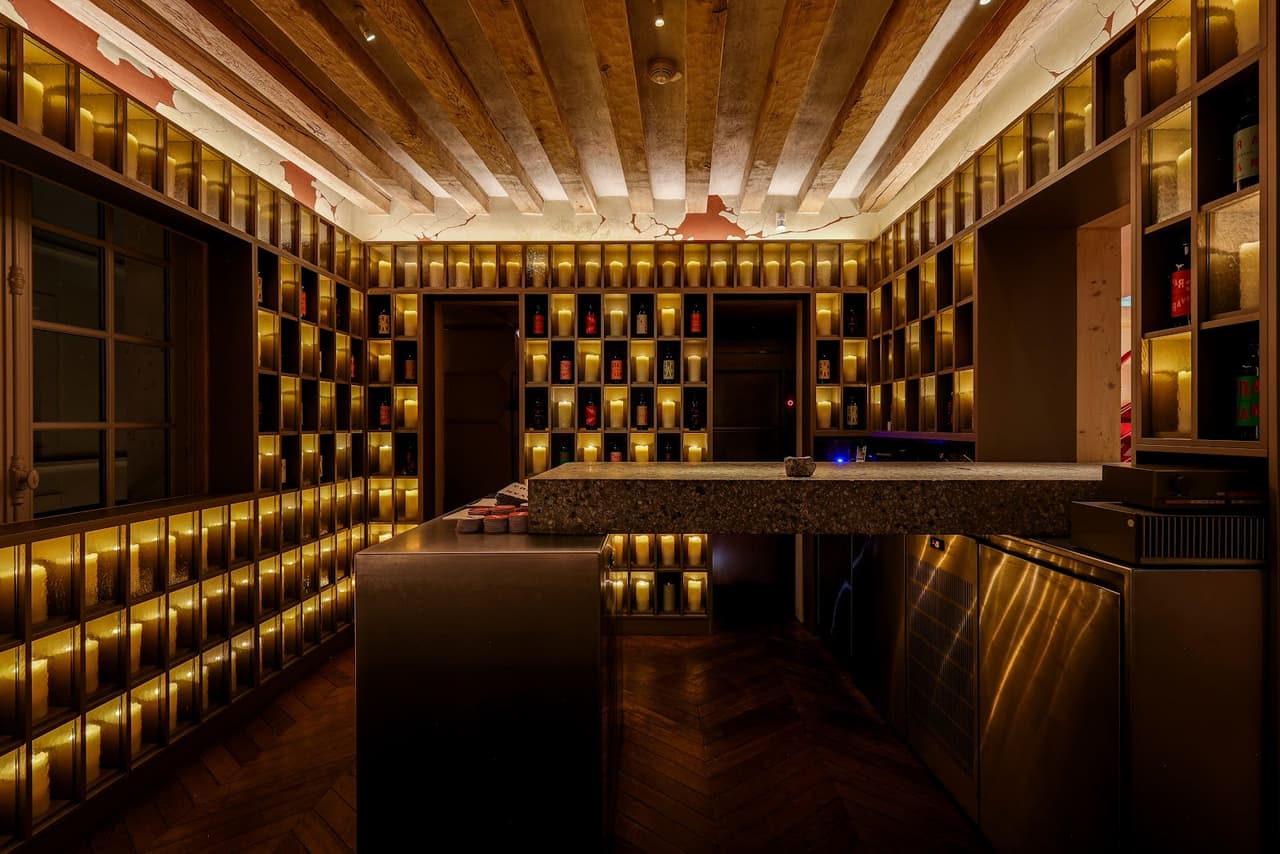 Stylish bar interior with illuminated shelves and wooden ceiling decor in Paris