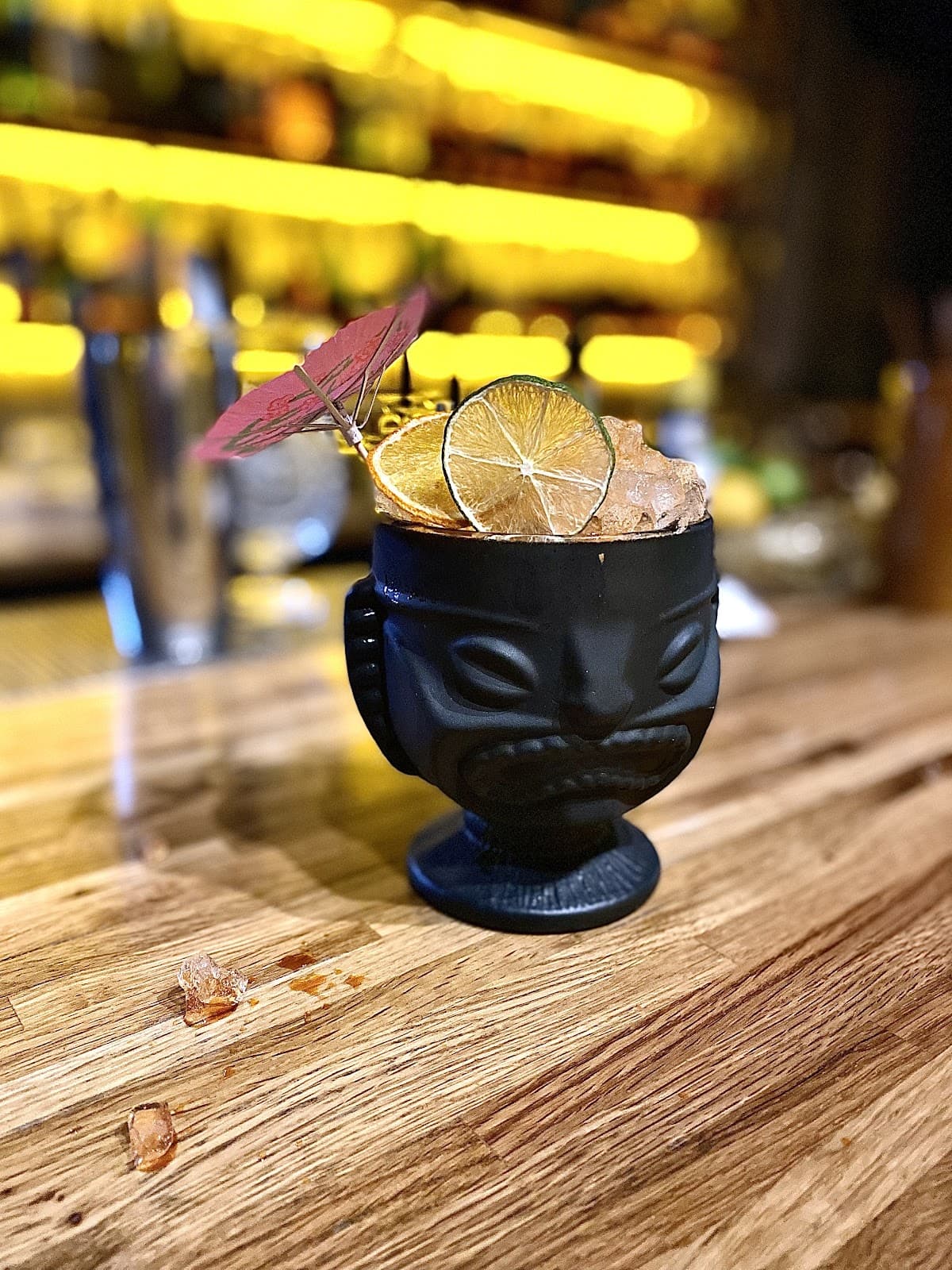 Stylish cocktail with lime slices and umbrella on a wooden bar counter in Toronto