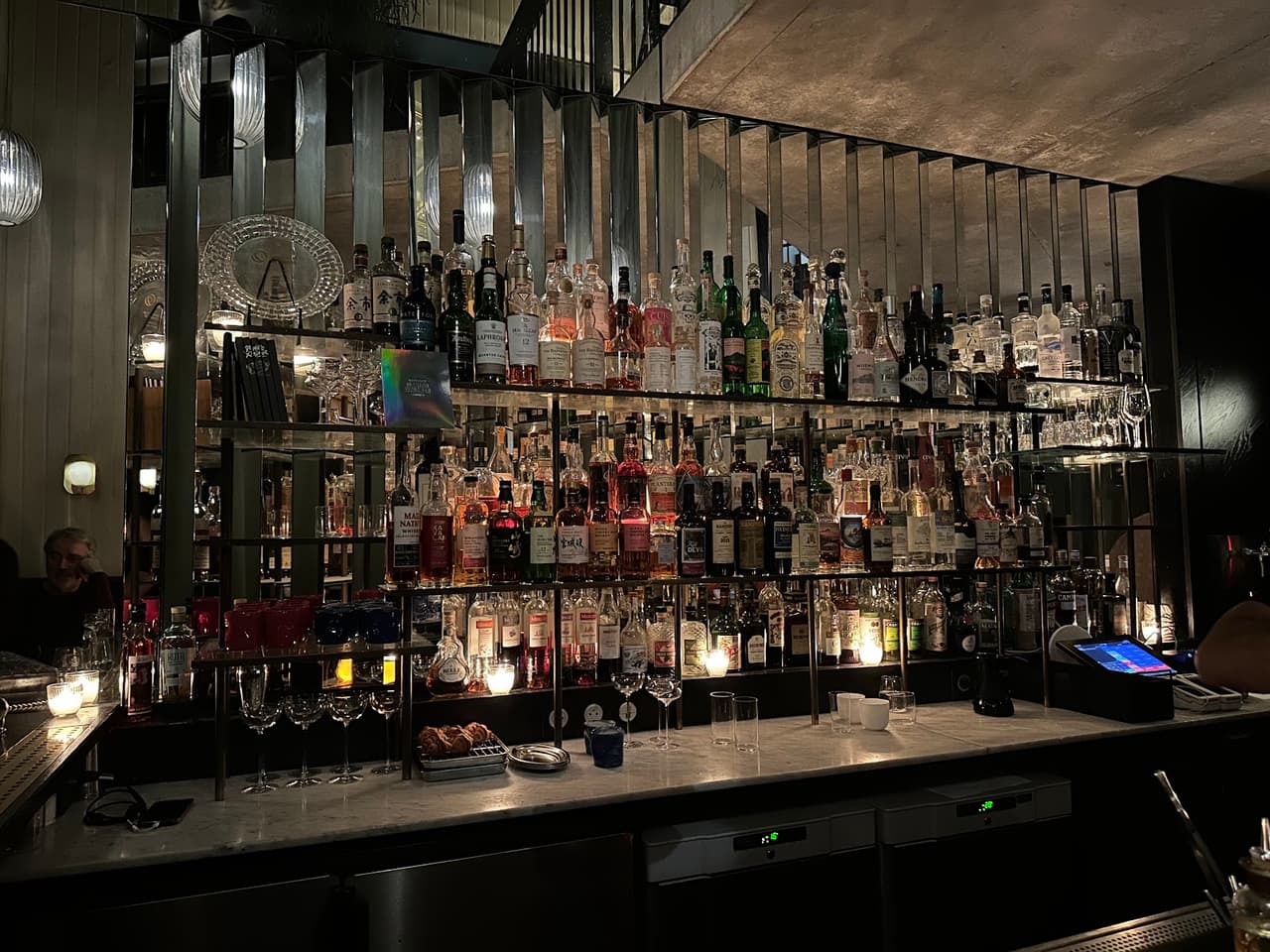 Dimly lit bar with a variety of liquor bottles and glassware on display in Paris