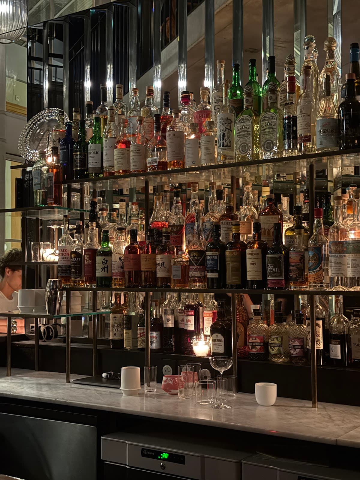 Well-stocked bar with mirrored shelves and dim lighting in Paris