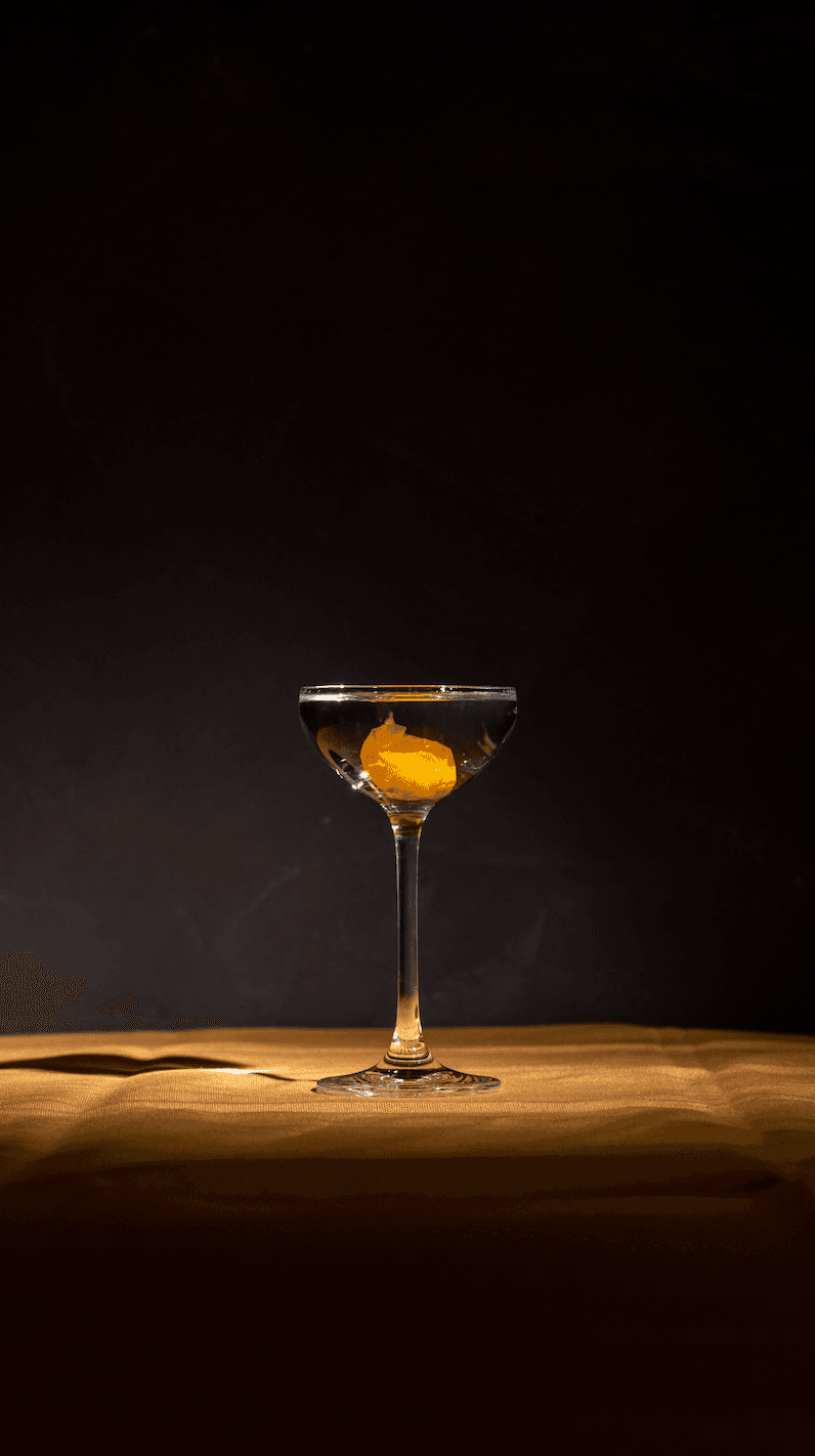 Elegant cocktail with an orange garnish in a dimly lit setting in Paris