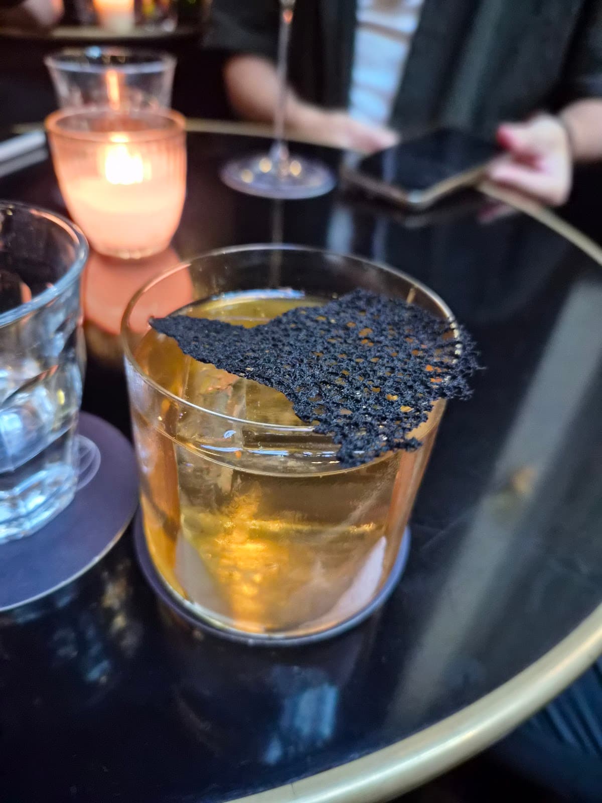 Elegant cocktail with dark garnish on round table in Paris