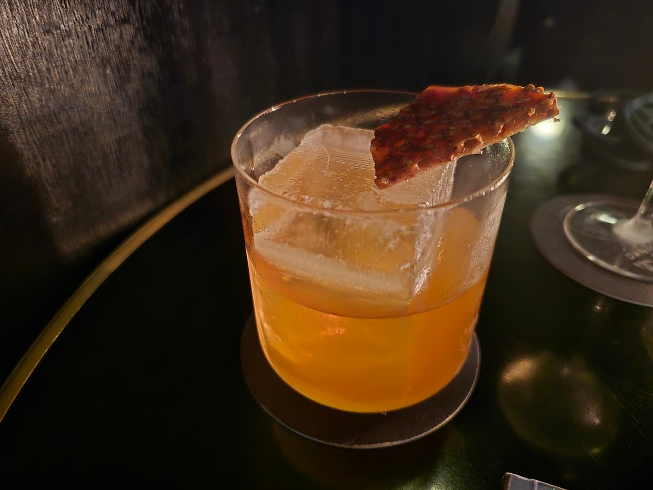 Elegant cocktail with large ice cube and garnish on a dark table in Paris