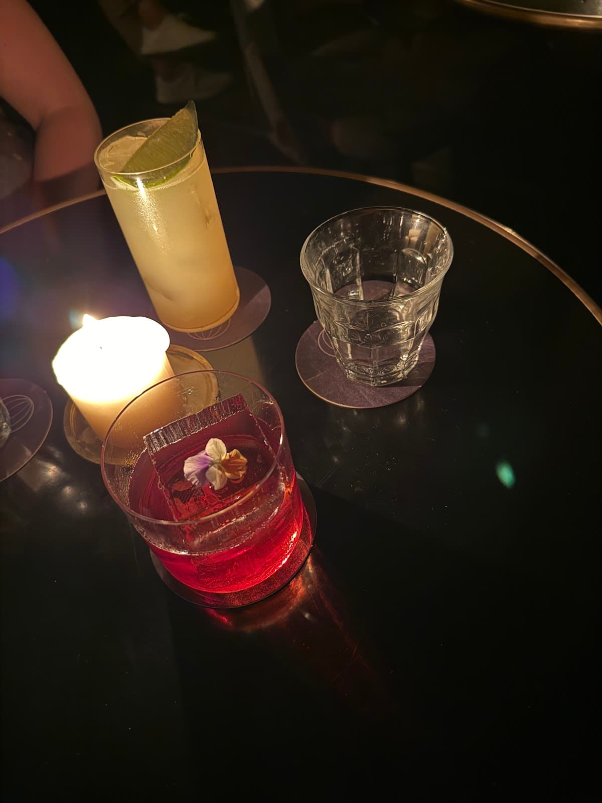 Cocktail glasses on a dimly lit table with a candle in Paris