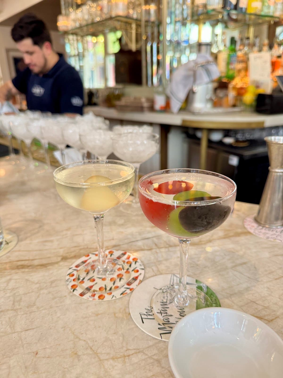 Close-up of cocktails on a marble bar counter with bartender in background in New York