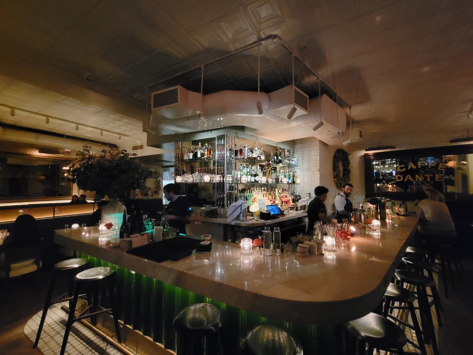 Warmly lit bar counter with bottles and bartenders at Caffe Dante in New York