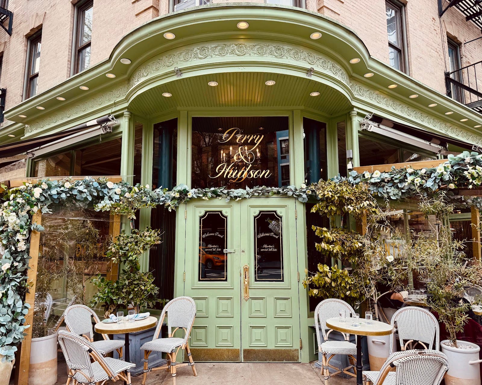 Stylish exterior of Perry & Hudson with green decor and outdoor seating