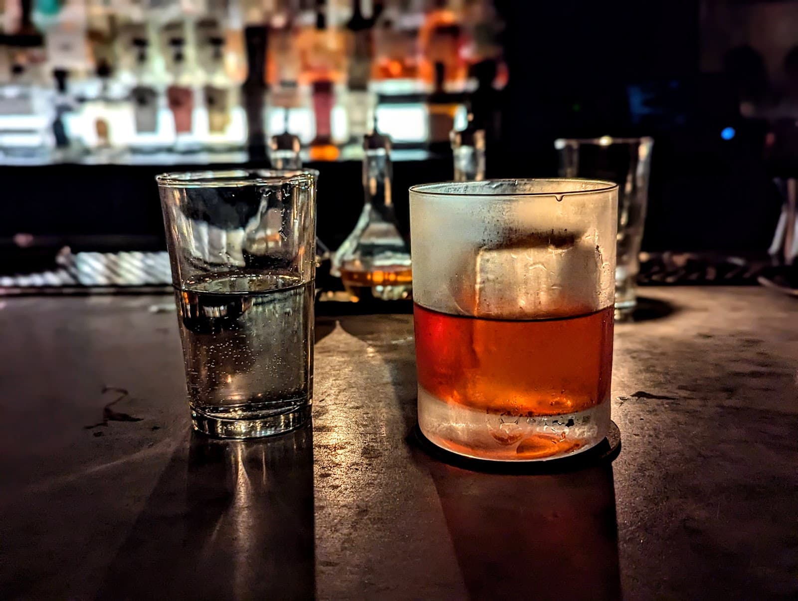 Close-up of a cocktail glass with ice on a dimly lit bar counter in New York