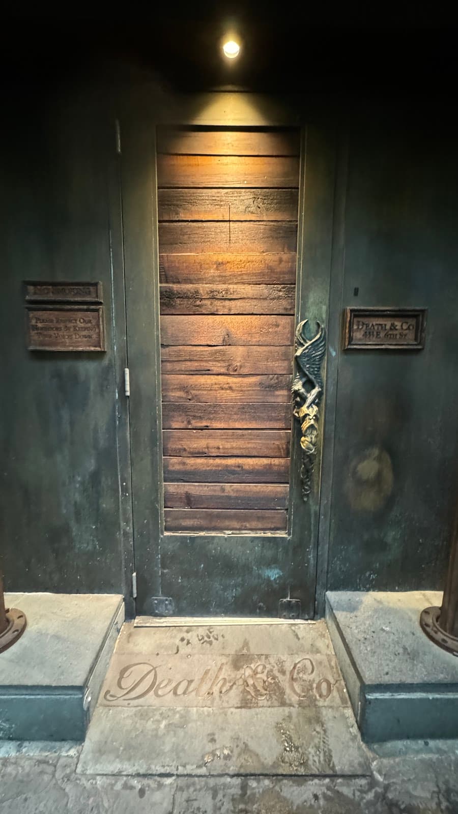 Entrance to Death & Co with wooden door and dim lighting in New York