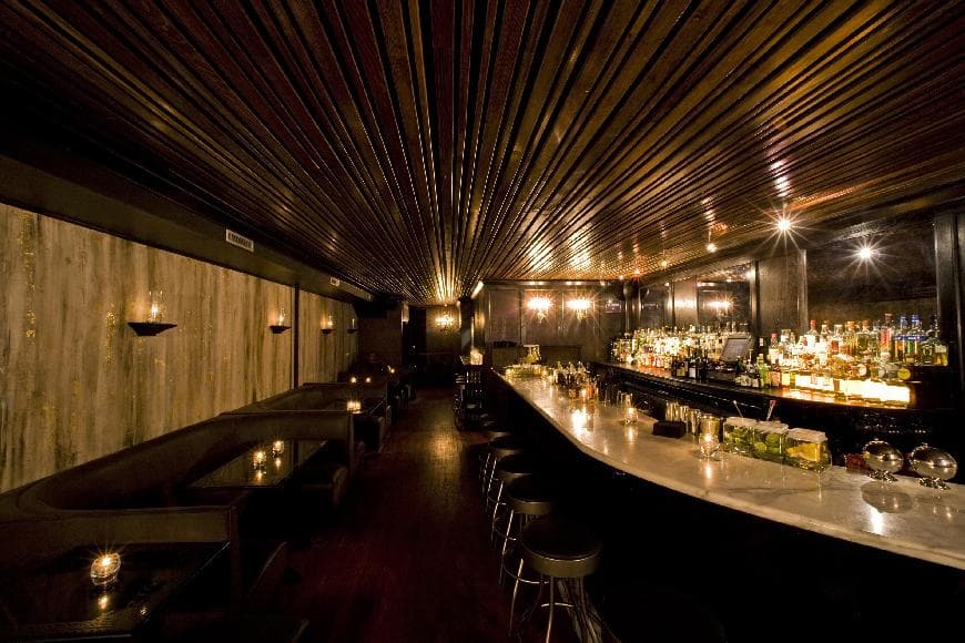 Dimly lit bar interior with a white counter and bottle display