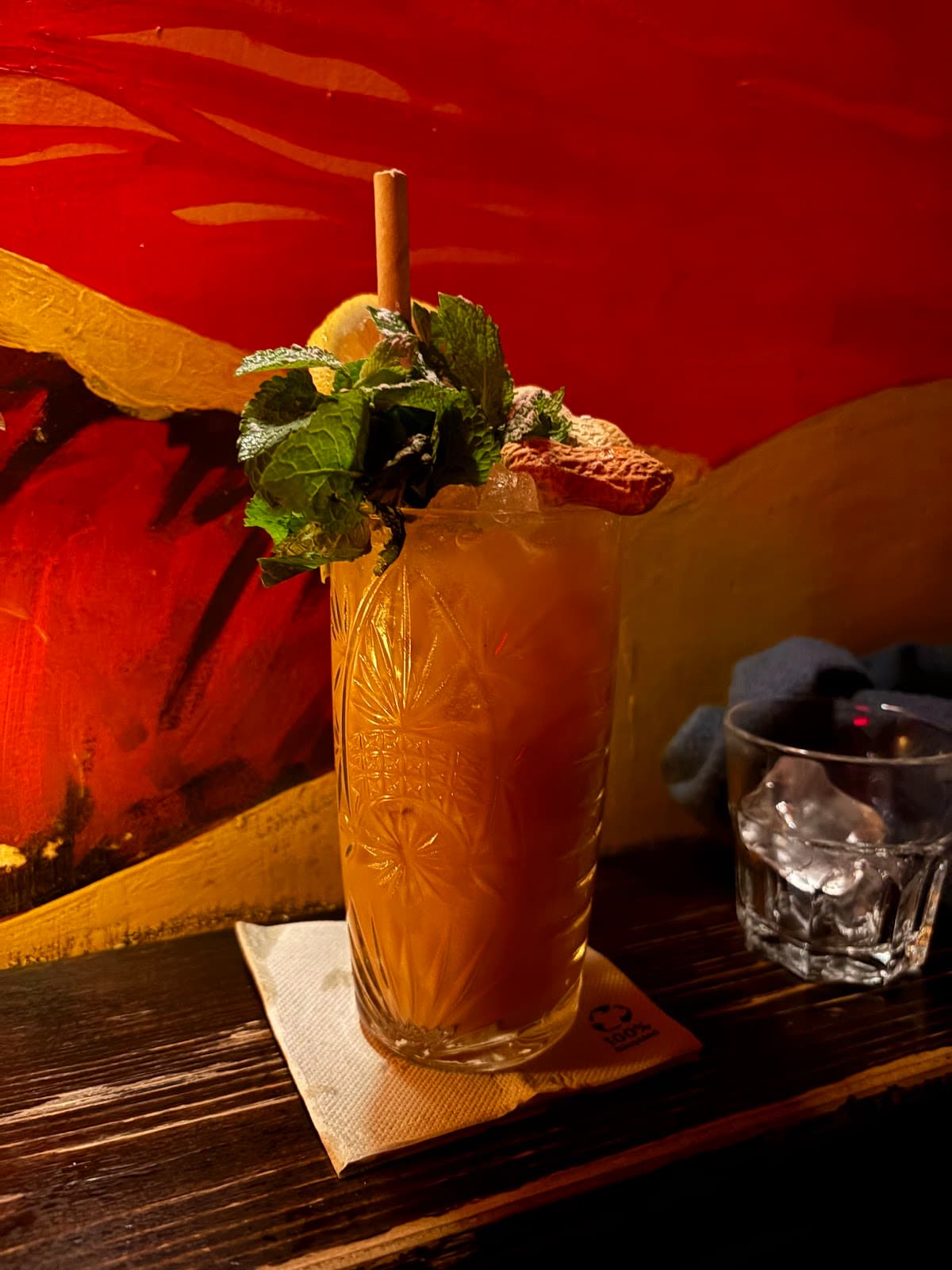 Decorative cocktail with mint served on a napkin on a wooden bar counter in Paris