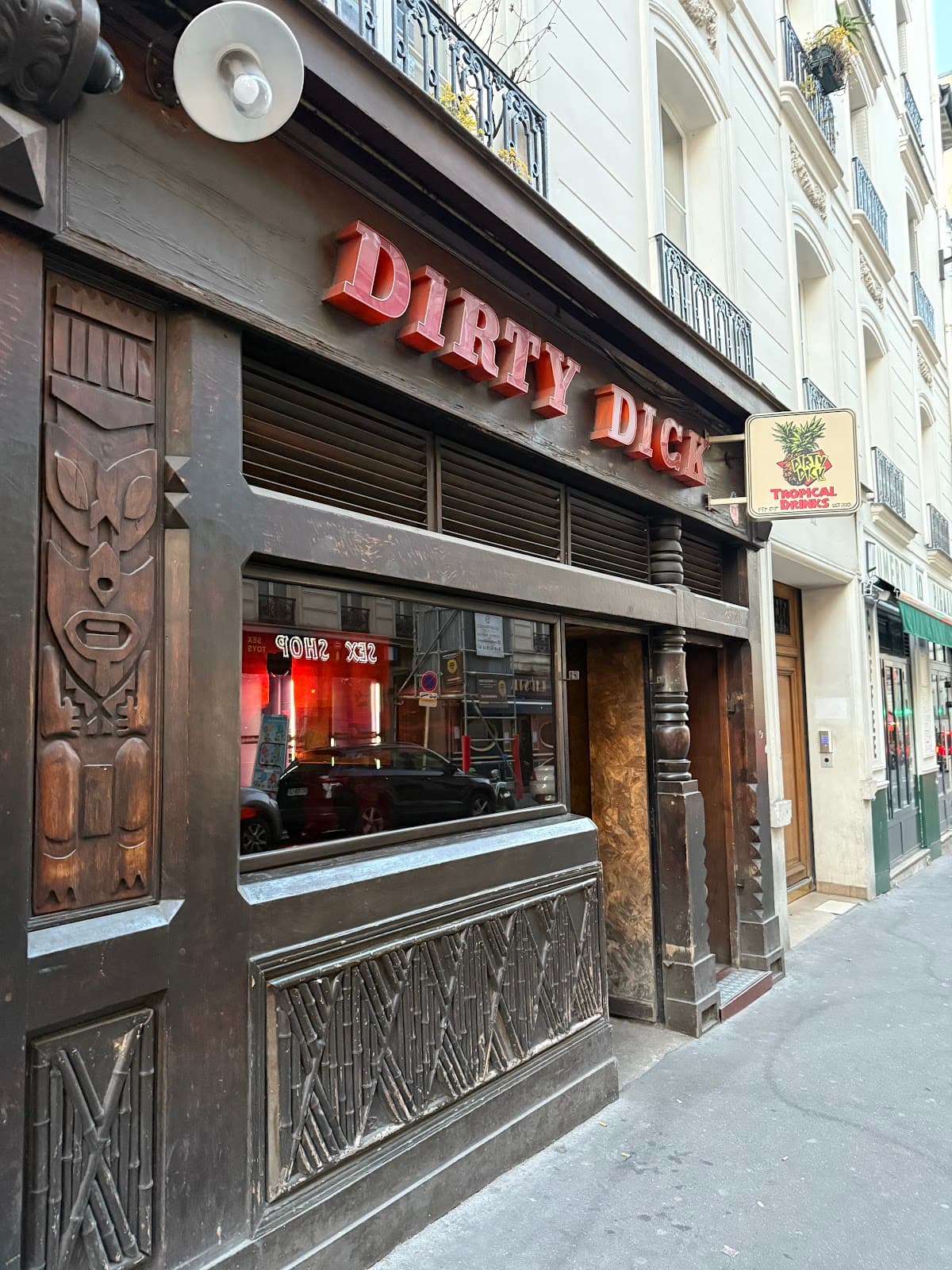 Exterior of Dirty Dick cocktail bar with carved wooden facade in Paris