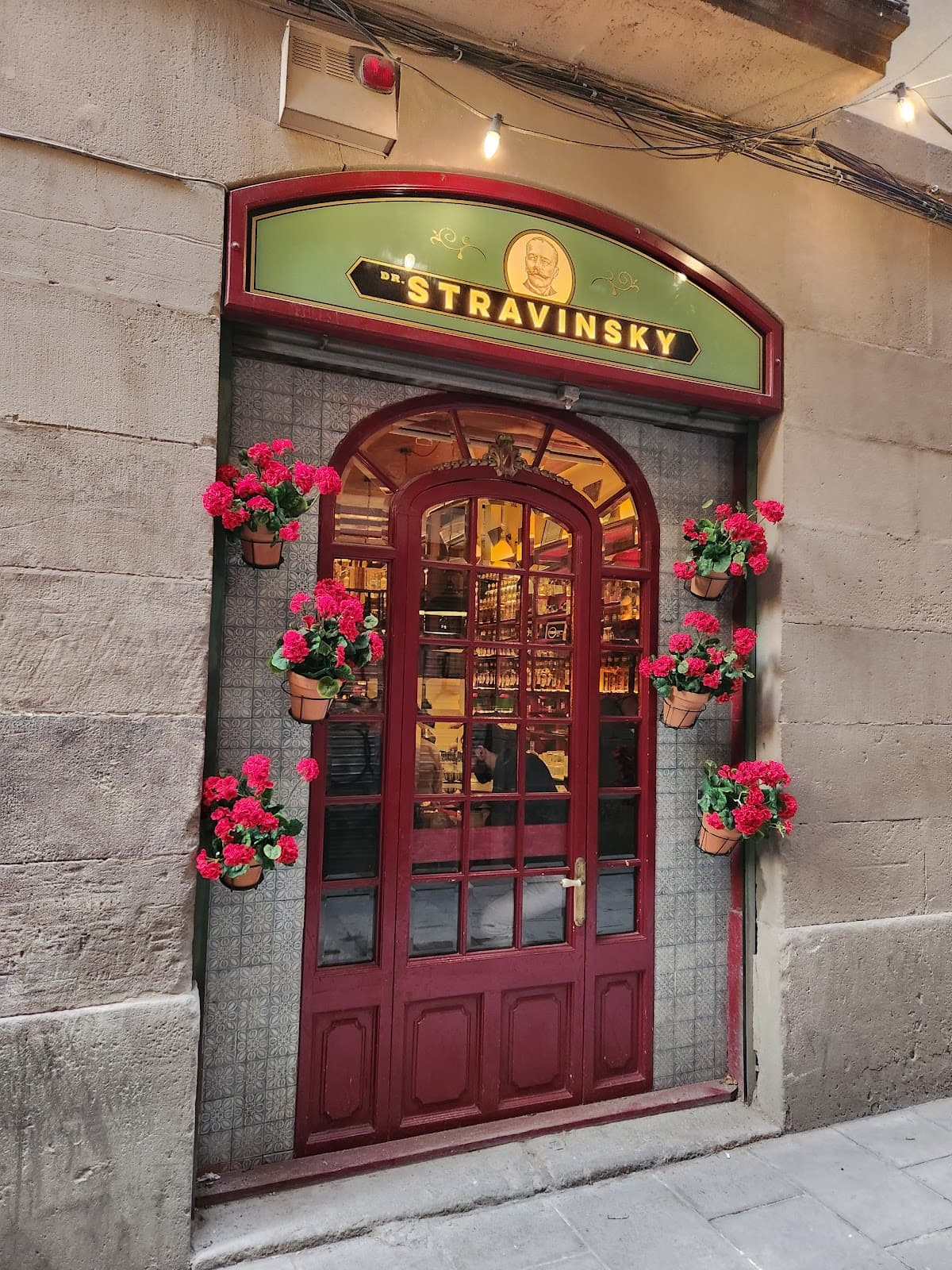 Exterior of Dr. Stravinsky bar with red door and flower pots. in Barcelona