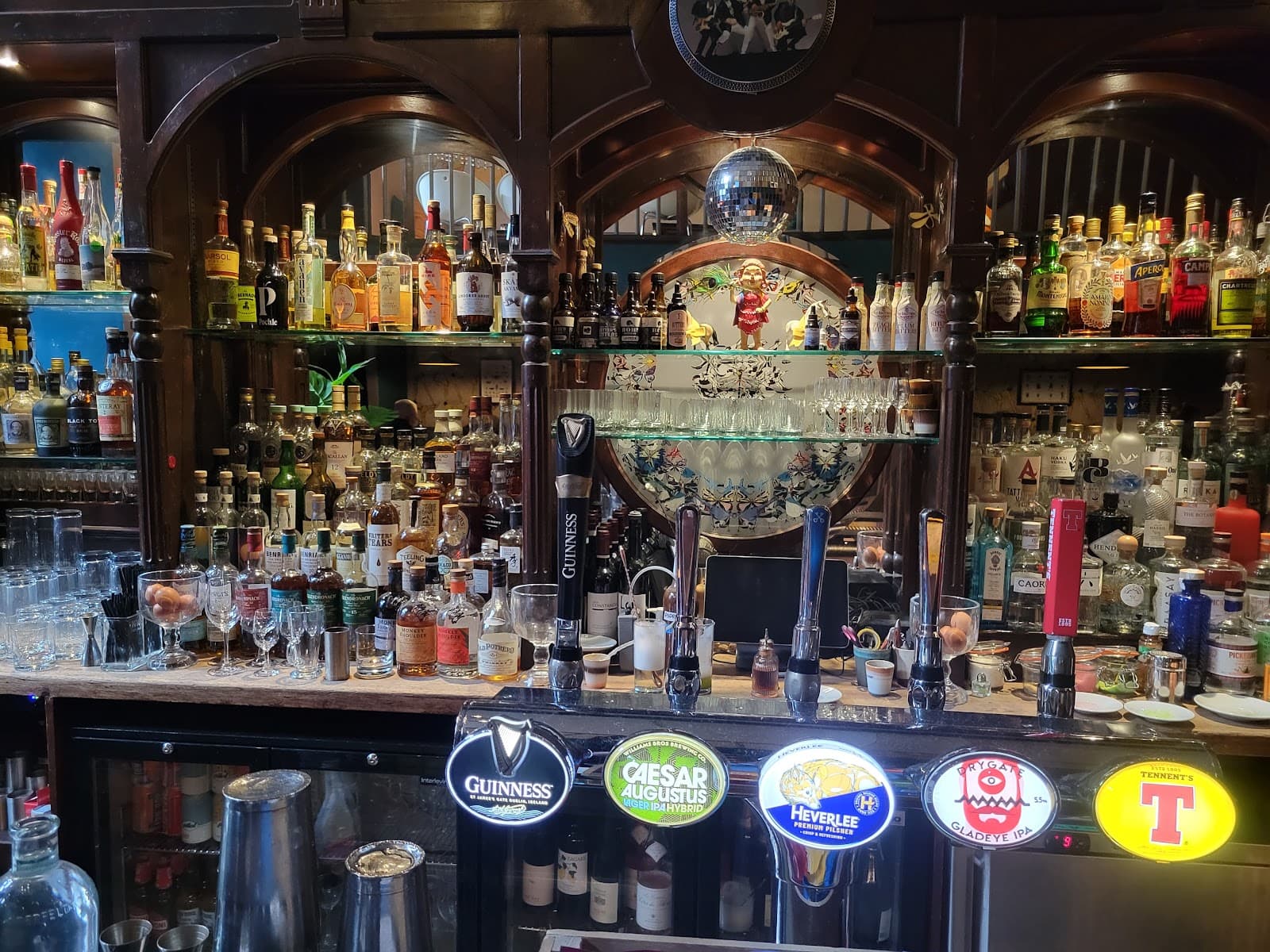 Close-up of a stocked bar with various bottles and beer taps prominently displayed in Edinburgh