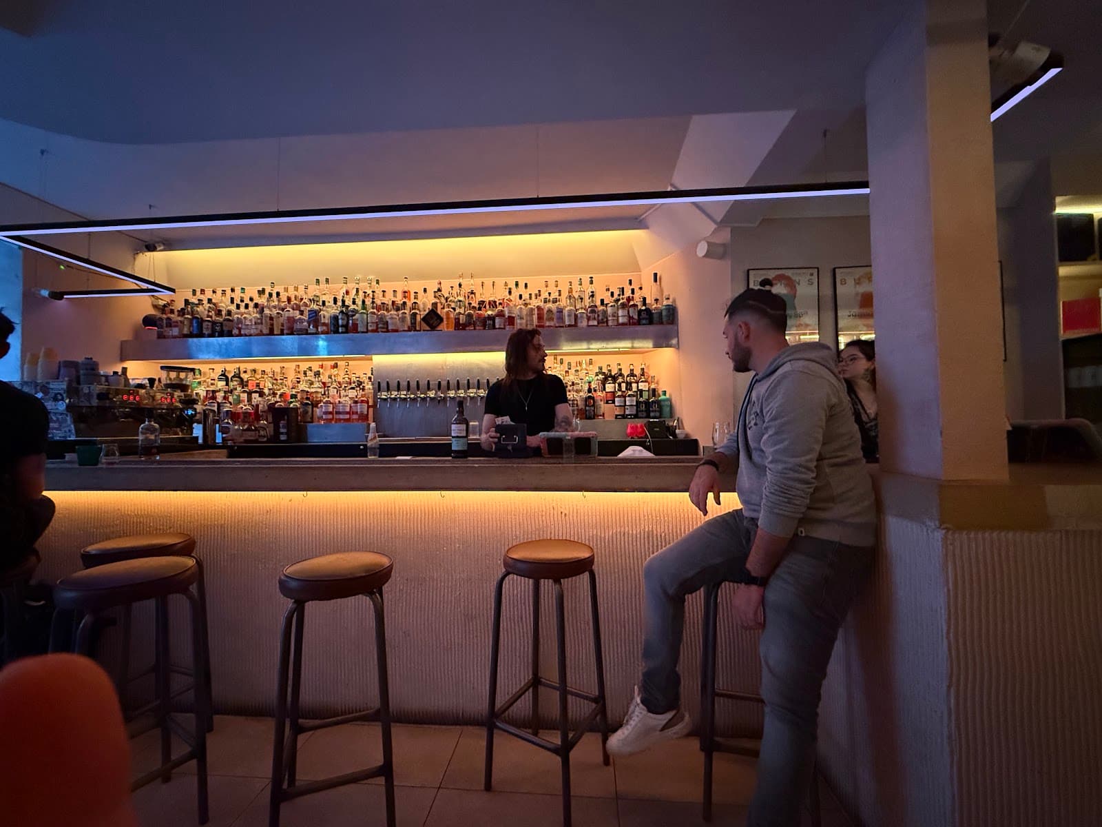 Bar counter with stools and illuminated bottle shelves in London