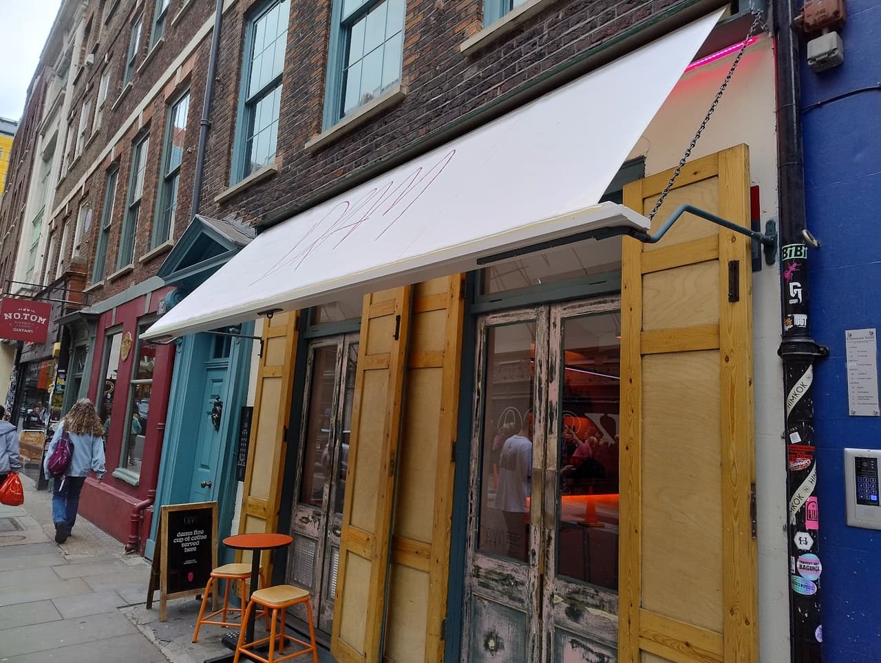 Exterior view of a cocktail bar with colorful storefront and seating