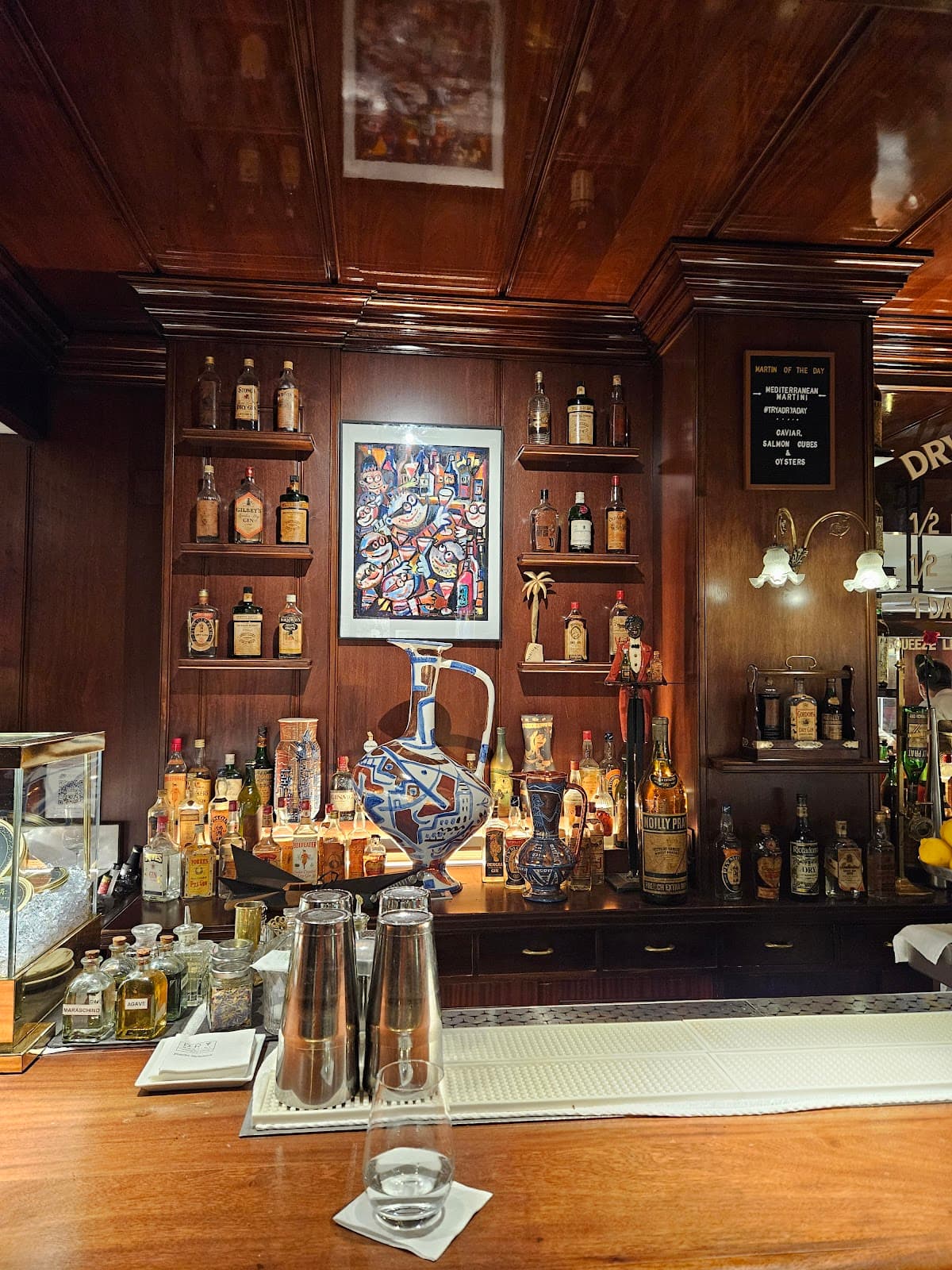 Well-lit bar counter with various bottles and decorative vases on display in Barcelona