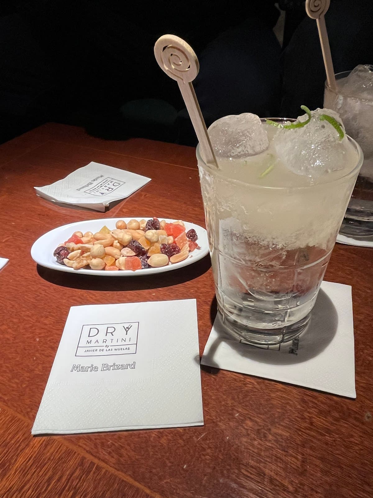 Cocktail on table with napkin labeled Dry Martini, plate of snacks in the background in Barcelona