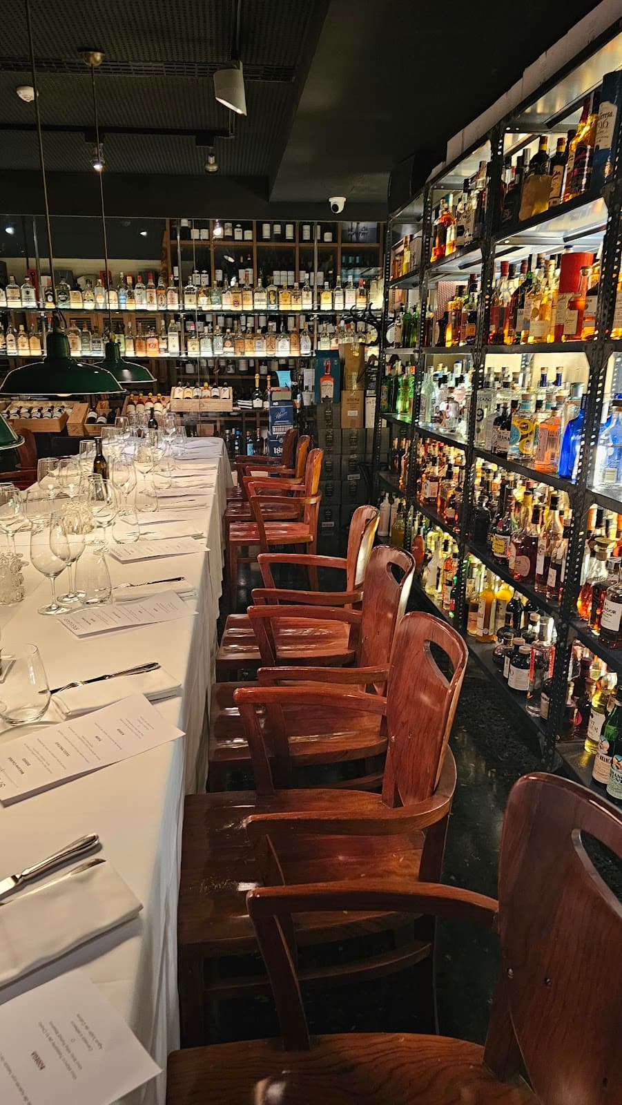 Elegant interior with a long table and shelves of bottles at a cocktail bar in Barcelona