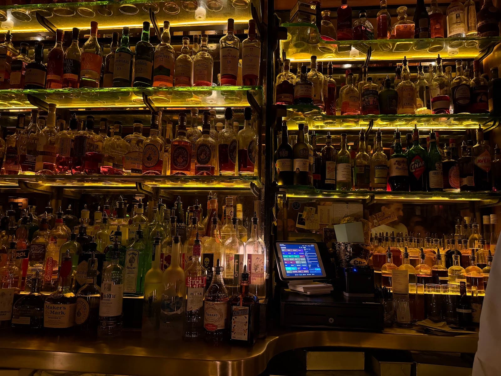 Illuminated bar counter with various bottles displayed on shelves in New York