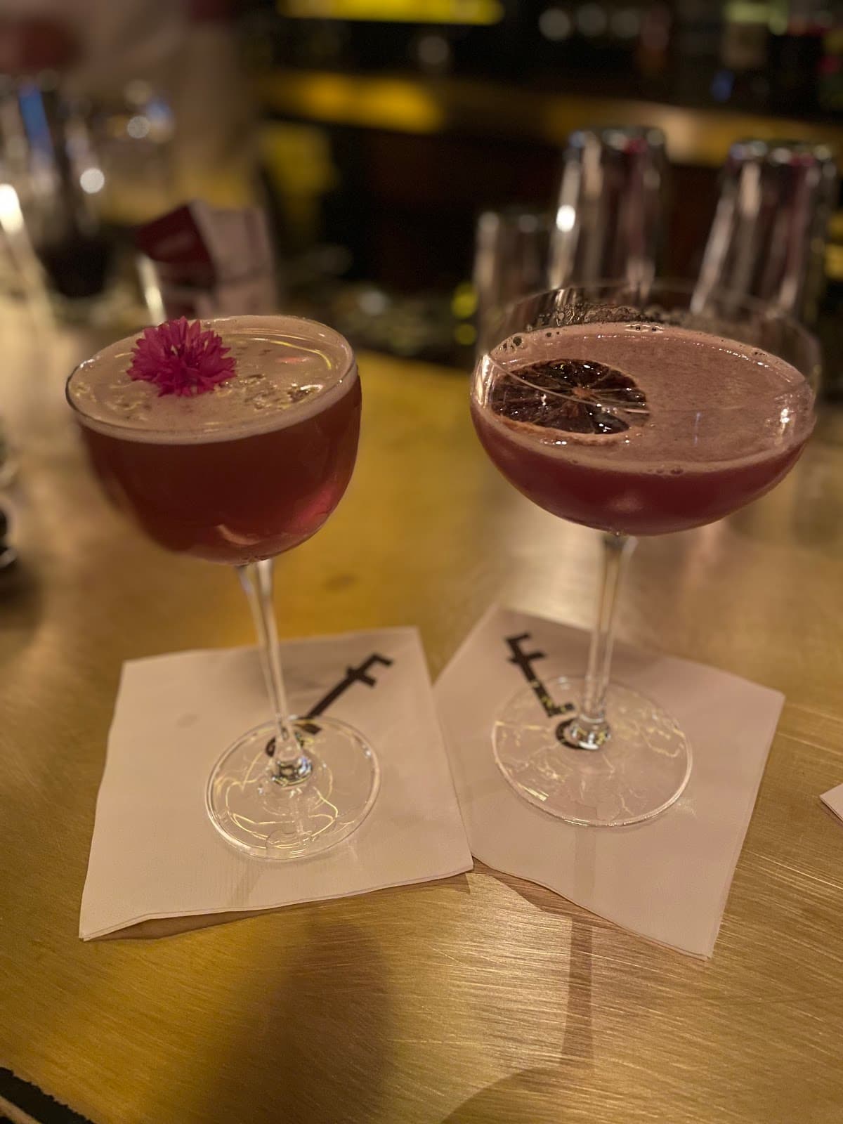 Two cocktails on a bar with a flower and citrus garnish in New York