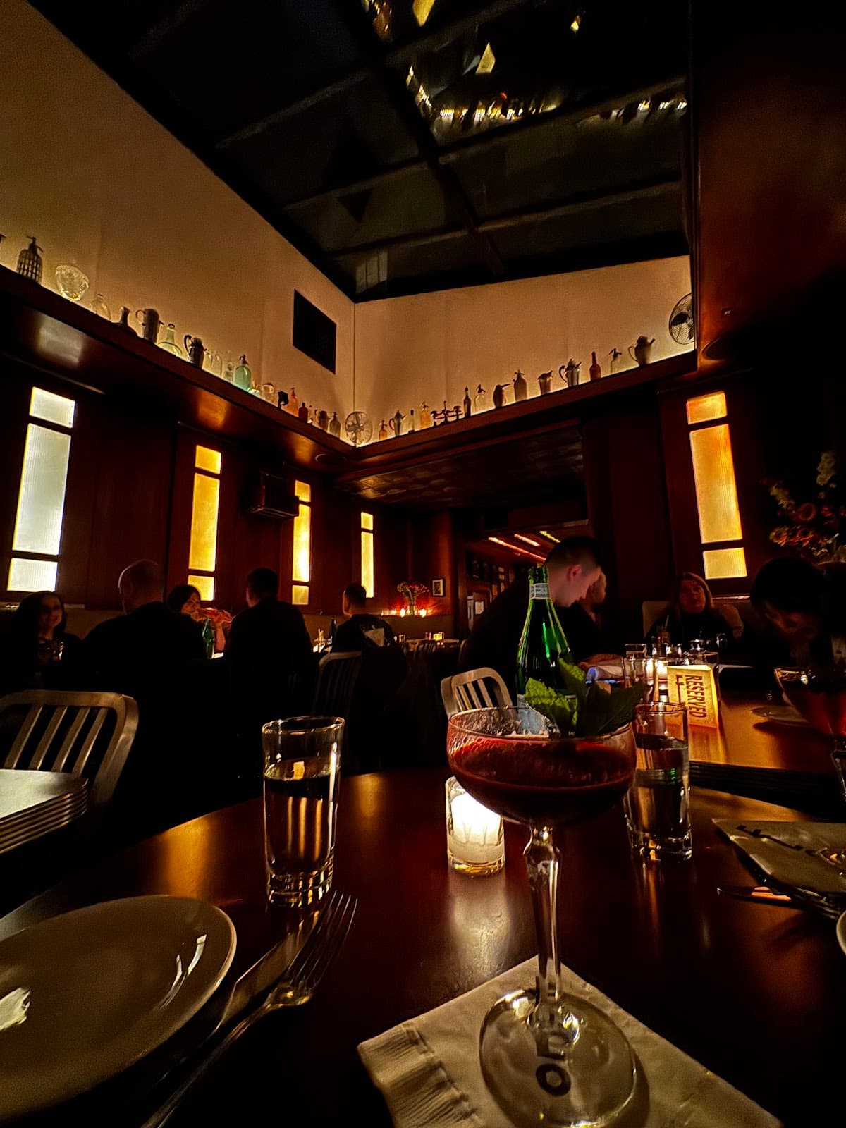 Dimly lit interior with patrons dining and a cocktail on the table in New York
