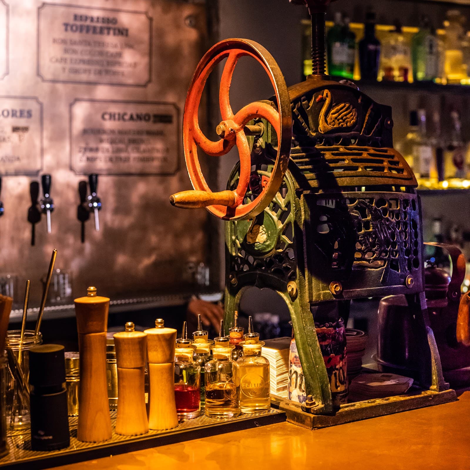 Close-up of vintage juicer and bottles on a dimly lit bar counter in Barcelona