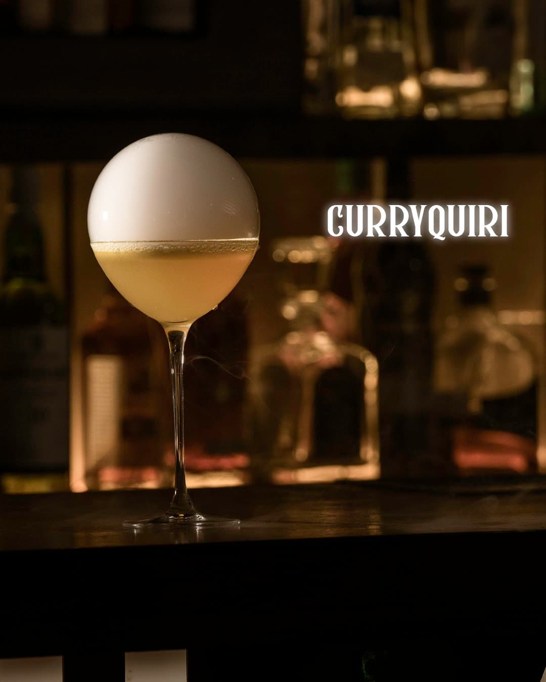 Elegant cocktail with a frothy top on a bar counter at Curryquiri in Barcelona