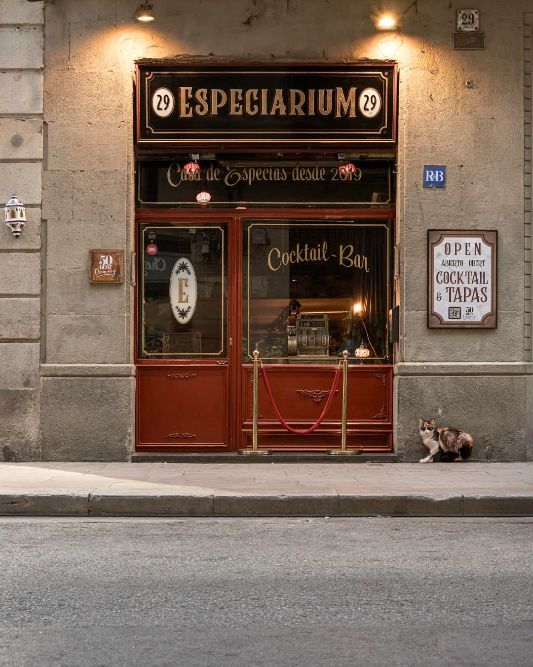 Exterior of Especiarium cocktail bar with a cat on the sidewalk in Barcelona
